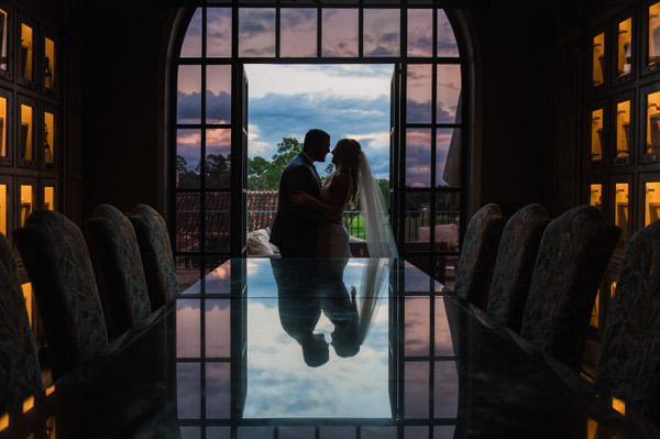 Bride in groom in glowing wine room at The Club at Houston Oaks with silhouette and reflection happening in the table