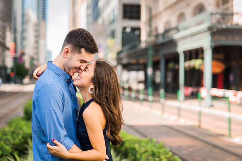 Couple laughing on Main Street in downtown Houston during engagement session