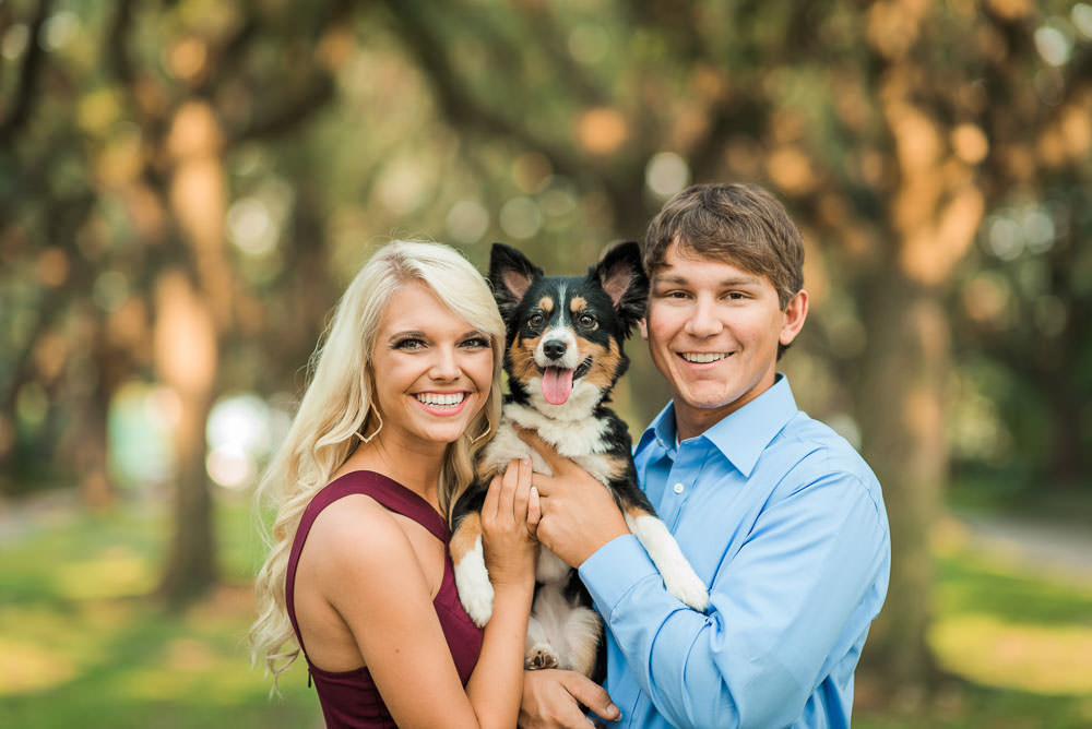 Bride and Groom smiling at the camera with their dog in between them for Houston Engagement Portraits