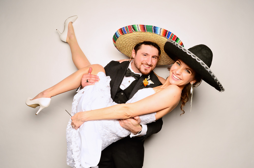 Groom holding Bride while both are wearing sombreros